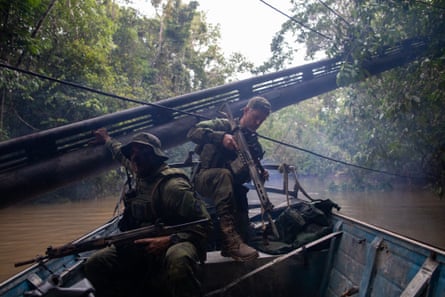 People in military camouflage gear on a boat in a jungle