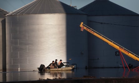 A boat passes by grain bins that are surrounded by floodwater on 21 March, in Craig, Missouri