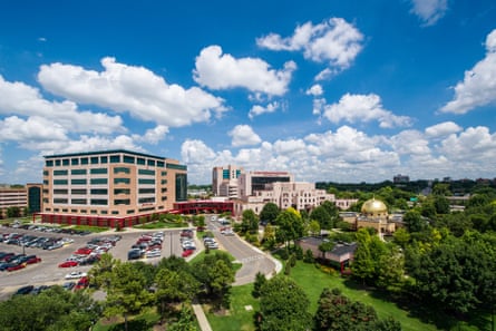 Aerial view of the campus of St Jude children’s research hospital, shows a large hospital building, a grassy area with trees, a car park, some smaller ancillary buildings and a building with a golden dome.