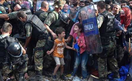 Children cry as migrants waiting on the Greek side of the border break through a cordon of Macedonian special police forces to cross into Macedonia, near the southern city of Gevgelija on 21 August 2015.