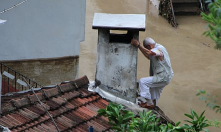 A man climbs to a chimney to rescue himself from the flood after heavy rains cause floods in Inebolu district of Kastamonu, Turkey