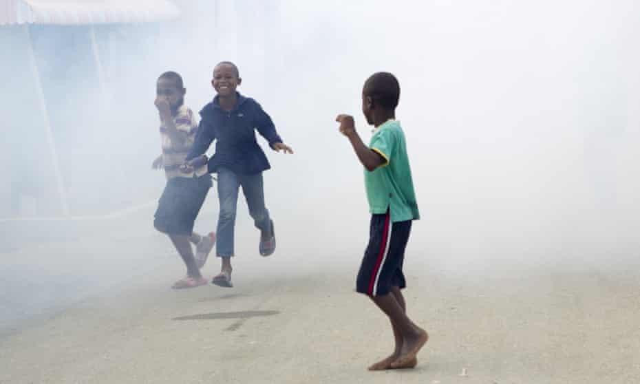 Children in the Dominican Republic running from fumes as air force personnel fumigate against the Aedes aegypti mosquito, vector of the Zika virus.