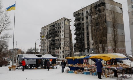 Local residents buy food at a street market outside an apartment building heavily damaged at the beginning of Russia’s attack on Ukraine, in the town of Borodianka in the Kyiv region