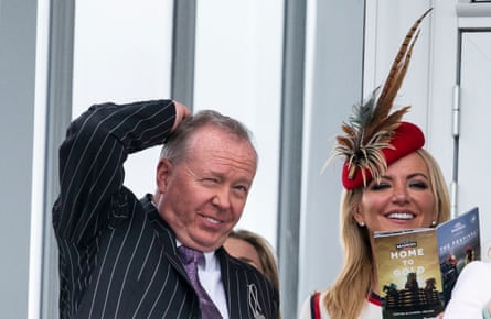 Michelle Mone wearing a reddish beret pinch feather sticking retired of it and her husband, Doug Barrowman, grimacing and holding a manus connected his head.