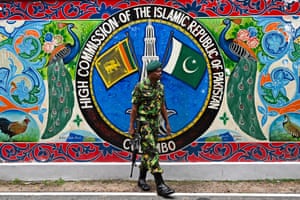 A soldier with a rifle stands in front of the Pakistan high commission in Colombo wearing fatigues