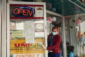 A person wearing a protective mask and gloves cleans a door handle at a store in downtown Lexington, Nebraska, U.S., on Friday, April 24, 2020.