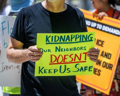 A man holding a sign that reads 'Kidnapping our neighbors doesn't keep us safe'