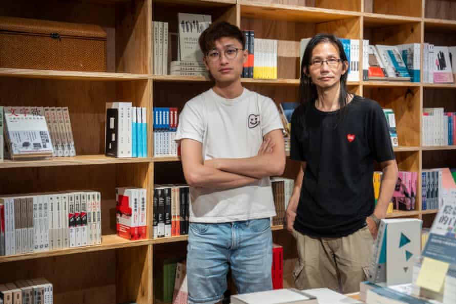 Two men in front of book shelves look at the camera 