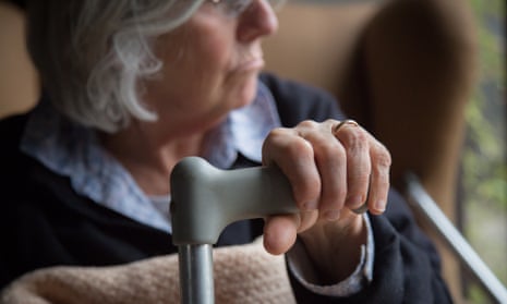 An older person sits in a chair at home.