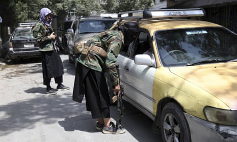 Taliban fighters search a vehicle at a checkpoint on the road in the Wazir Akbar Khan area of Kabul, Afghanistan, on Sunday.