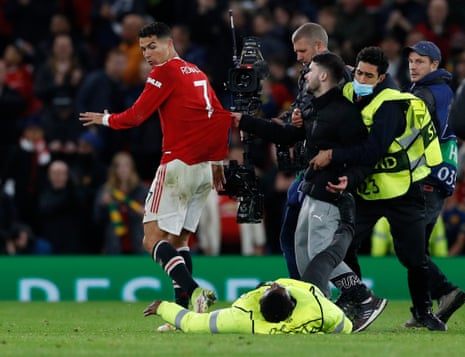 A pitch invader runs up to Manchester United’s Cristiano Ronaldo as stewards stop him.