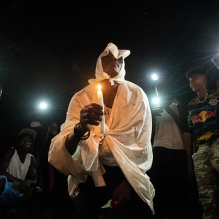 A man dressed in white clothing holds a candle