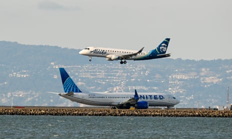 A United Airlines plane takes off as an Alaska Airlines plane is landing at San Francisco international airport. Both airlines are in dispute with flight attendants.
