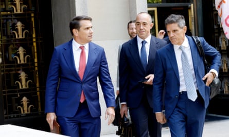 Three middle-aged men in suits walk together.