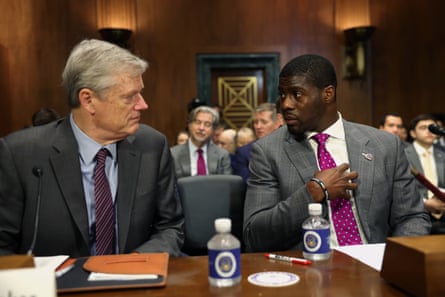 two men looking at each other in a government hearing room