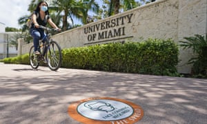 A cyclist rides by the entrance to the University of Miami.