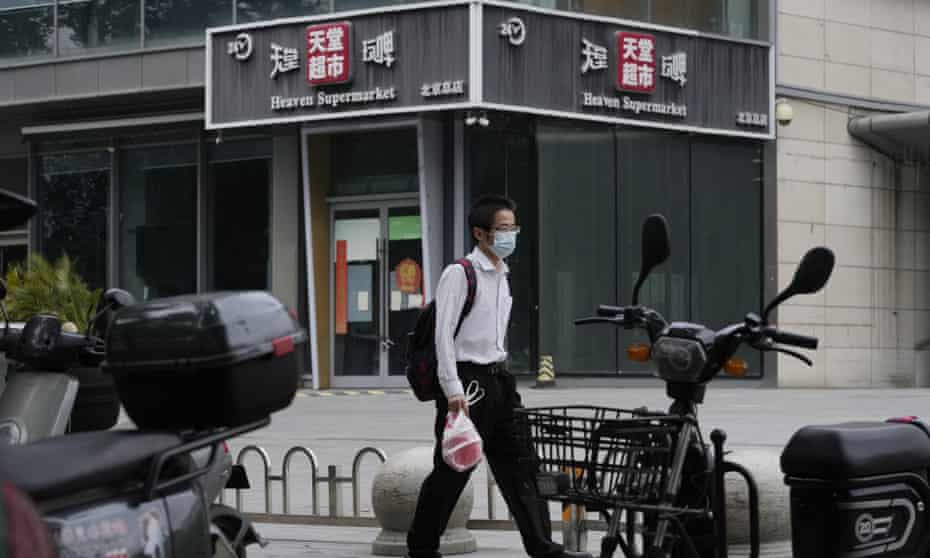 A man wearing a mask walks past the Heaven Supermarket bar in Beijing.