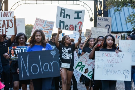 Young people hold signs saying 'Nolan' and 'Am I Next?'