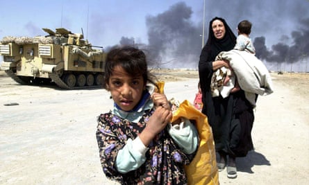 A family leaves burning Basra, Iraq, in March 2003.