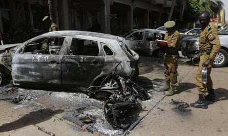 Soldiers take notes on a car that was burnt out outside the Splendid Hotel in Ouagadougou, Burkina Faso.