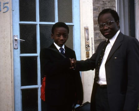 Yinka Bankole in school uniform posing with his father outside a front door