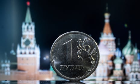 A Russian one rouble coin in front of a monitor showing St. Basil's Cathedral and a tower of Moscow's Kremlin.