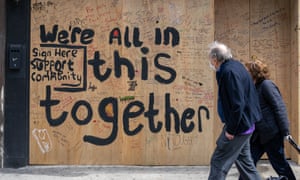 A couple walks by a boarded-up bar on the Upper East Side in New York, New York, on 20 April.