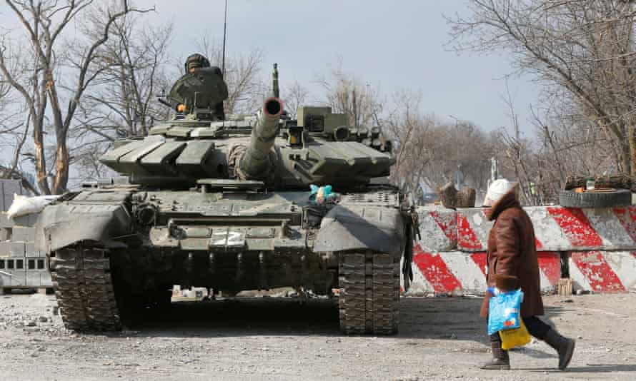 local resident walks past a tank of pro-Russian troops in the besieged city of Mariupol on Friday
