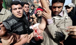 Egyptian protesters carry an injured officer as pro- and anti-Mubarak protesters clash in Cairo in February 2011.