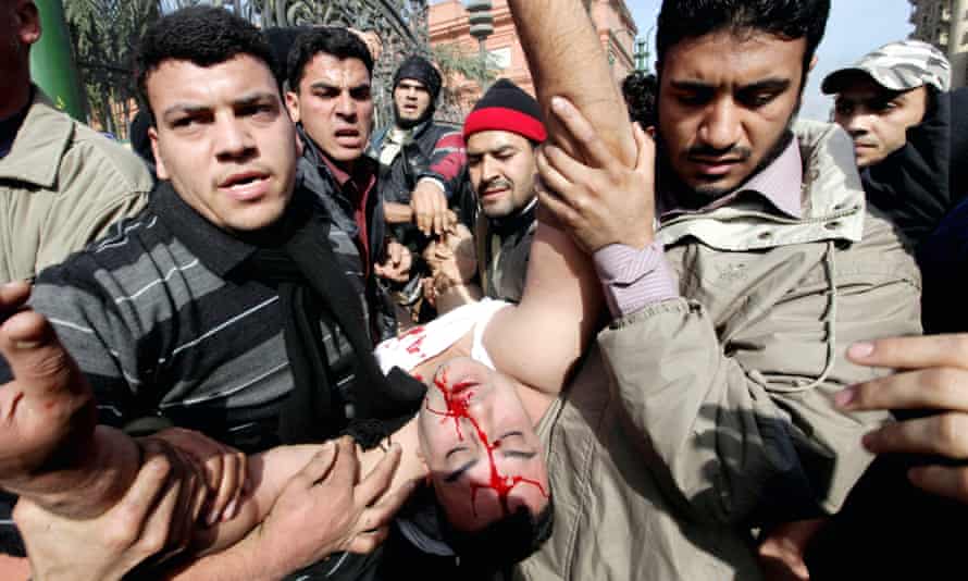 Egyptian protesters carry an injured officer as pro- and anti-Mubarak protesters clash in Cairo in February 2011.