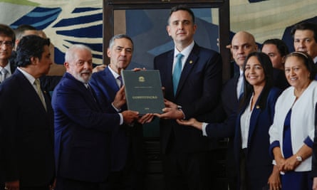Lula, the supreme court chief justice, Luís Roberto Barroso, the senate president, Rodrigo Pacheco, and the president of the superior electoral court, Alexandre de Moraes, pose with a Brazilian constution in Brasília on 8 January.