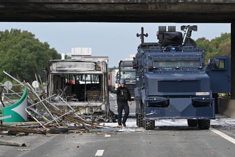 A French gendarme stands next to a bus burnt by protesters in the southern ring road in Rennes, during a demonstration as part of the ‘block everything’ protest, on Wednesday.