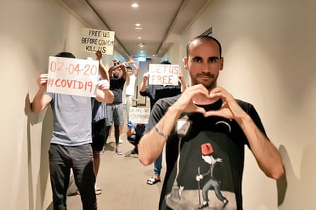 Moz Azimi in a corridor of a hotel with refugees holding signs