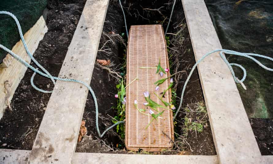 A wicker coffin in a new grave, after a burial service at a cemetery in England.