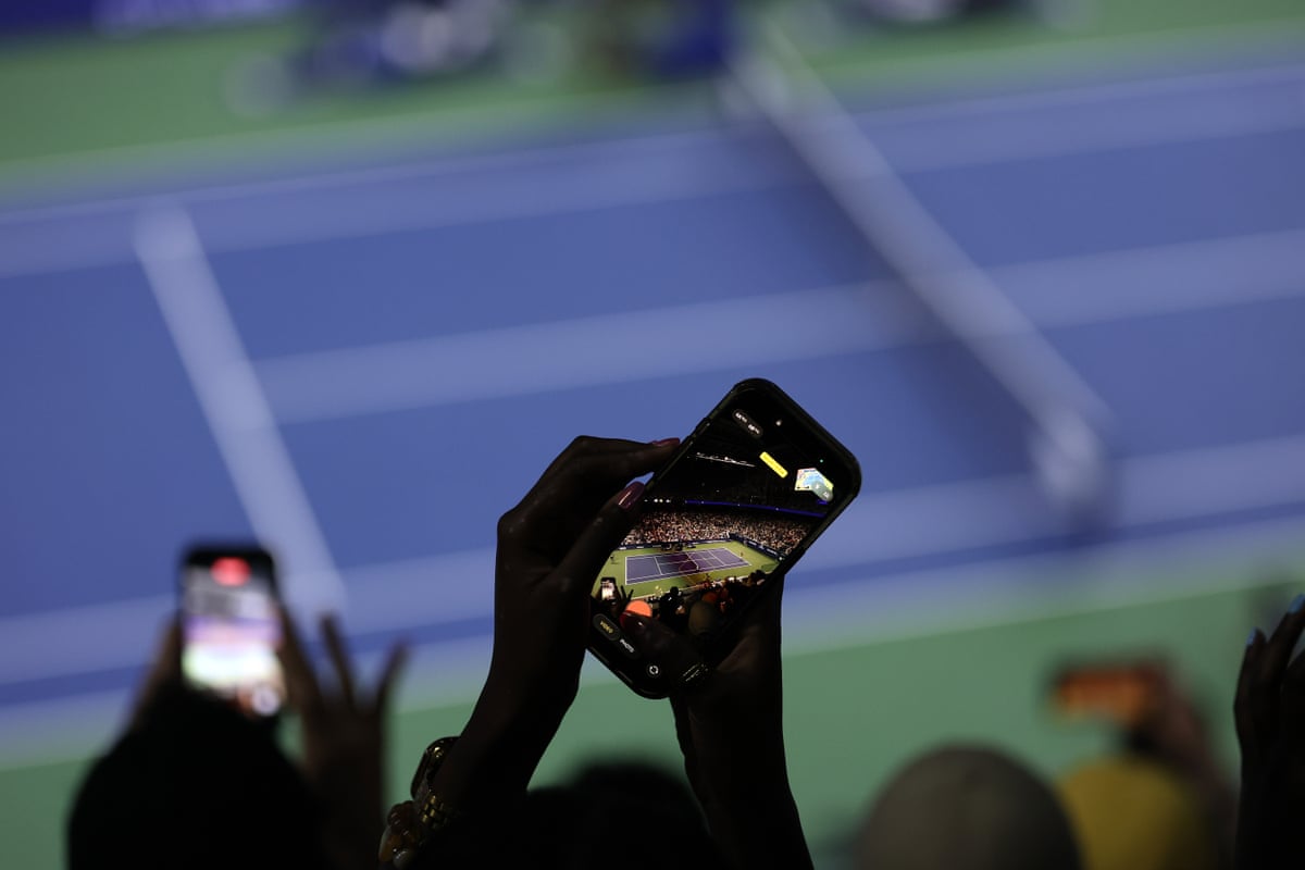 A fan takes a photo of the court during a night session at the US Open