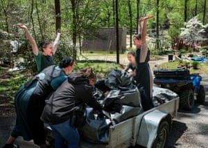 People raise their arms and cheer as they lift a heavy bag of debris on to a trailer
