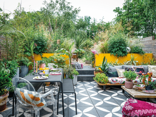 This lower-level, tiled space has tree ferns and palms in oversized planters, and bespoke large raised beds painted canary yellow