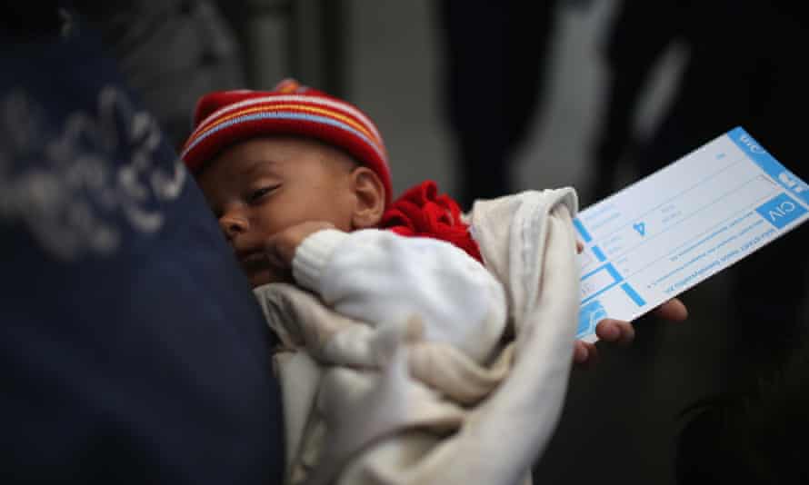 A mother holds her baby and a train ticket as they wait to board a train at Keleti station in central Budapest to take them to the Austrian border.