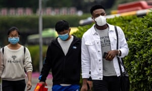 An African man and two Chinese people in face masks in Guangzhou