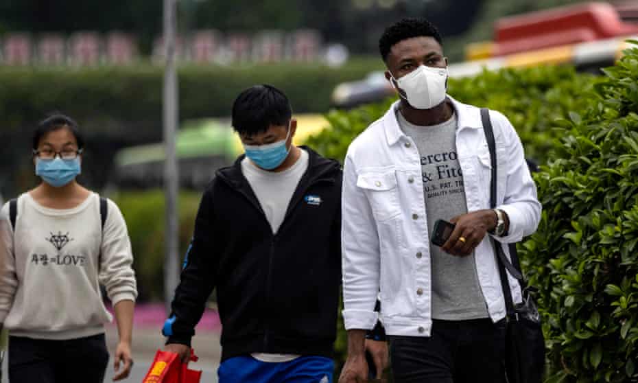 An African man and two Chinese people in face masks in Guangzhou
