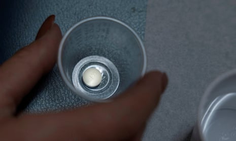 A woman holds a mifepristone pill in a plastic cup