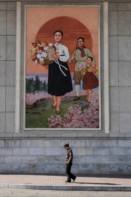 A man walks in front of a mural at the Pyongyang Grand Theatre