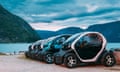 Electric cars parked in a row next to a lake surrounded by steep mountains in Eidfjord, Norway