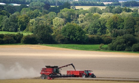 A tractor driving alongside a combine harvester as it unloads grain.