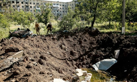 Ukrainian soldiers walk past the crater left by a shell in Vuhledar.