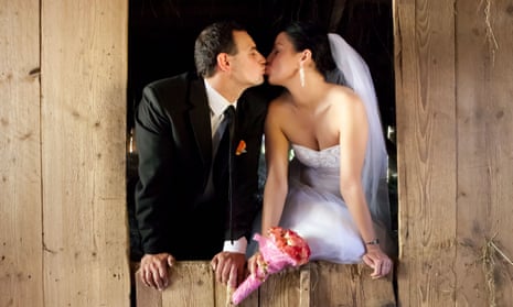A bride and groom kissing in a barn