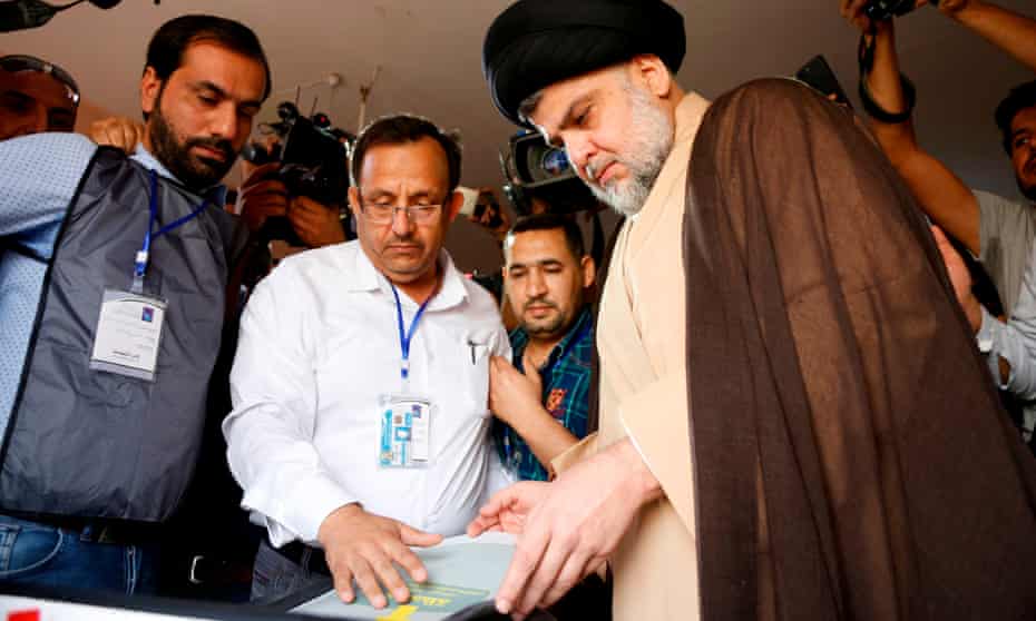 Iraqi Shia cleric Moqtada al-Sadr, right, casts his vote at a polling station in Najaf