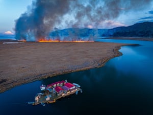 A floating village with wildfires in the background