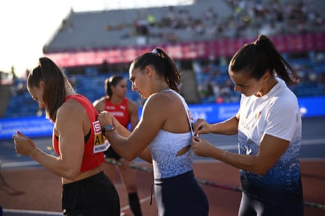 Switzerland's Angelica Moser (left) and fellow athletes help each other out with pinning their name tags on.