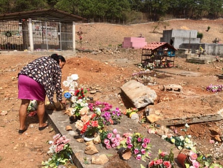 Floresmira Lopez rearranges flowers on her father’s grave